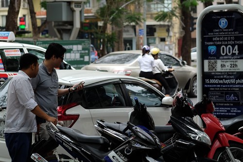 Hướng dẫn khách thanh toán phí đỗ xe qua điện thoại tại một điểm đỗ xe iParking. Ảnh: NGUYÊN VŨ