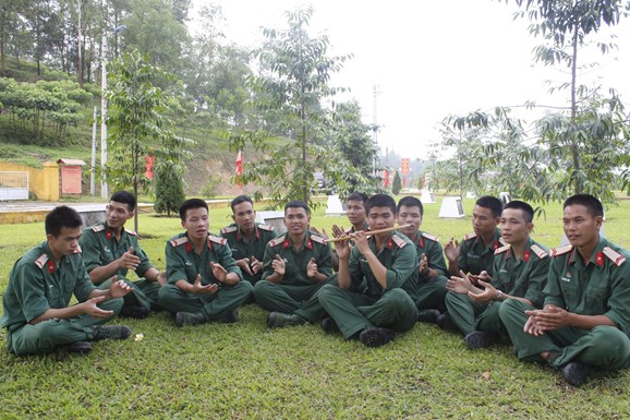 Binh nhì Lò Văn Hoàng thổi sáo cho đồng đội nghe.