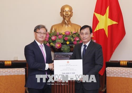 Thứ trưởng Bộ Ngoại giao Lê Hoài Trung (bên phải) trao tượng trưng số tiền Chính phủ Việt Nam hỗ trợ Chính phủ, nhân dân Lào khắc phục hậu quả sự cố vỡ đập thủy điện Sepien Senamnoi ở tỉnh Attapeu. Ảnh: TTXVN