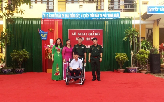 Đồn Biên phòng Pò Mã trao xe lăn tặng em Đinh Minh Tiệp trong chương trình "Nâng bước em đến trường". Ảnh: NGỌC KHANH.