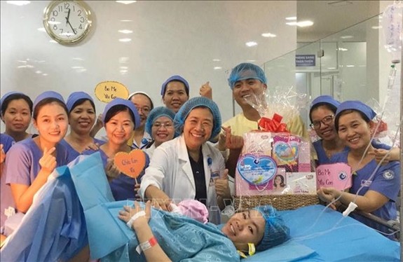 Ban giám đốc, ê-kíp trực đêm tại Bệnh viện Từ Dũ tặng quà cho sản phụ sinh con đầu tiên trong năm 2020. Ảnh: TTXVN
