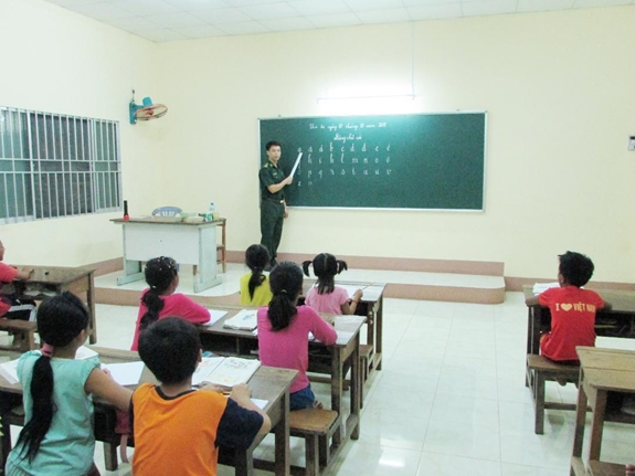 Thượng úy Đào Đình Luyện, cán bộ Đồn Biên phòng Tuyên Bình (Vĩnh Hưng, Long An) dạy chữ cho các em nhỏ trên địa bàn.