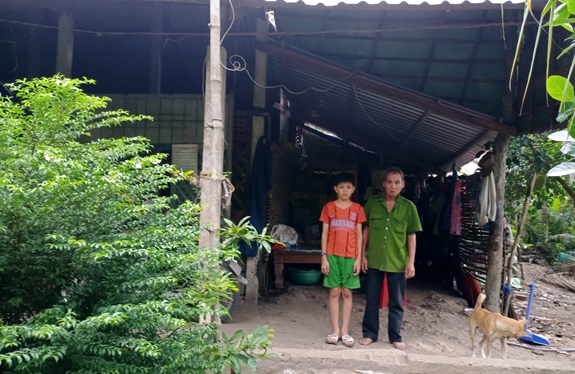 Cựu chiến binh Phạm Văn Công cùng cháu ngoại bên ngôi nhà đã xuống cấp.