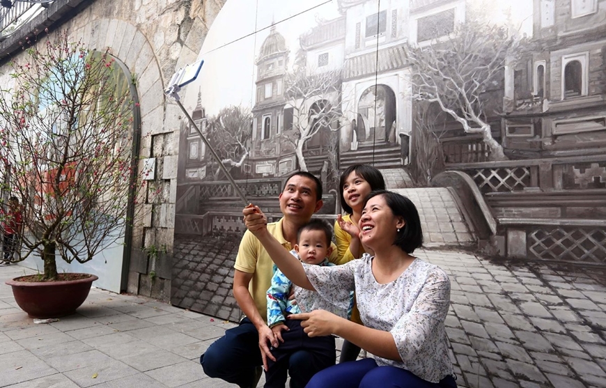 Người dân thủ đô chụp ảnh lưu niệm tại phố Bích họa Phùng Hưng. Ảnh: TTXVN